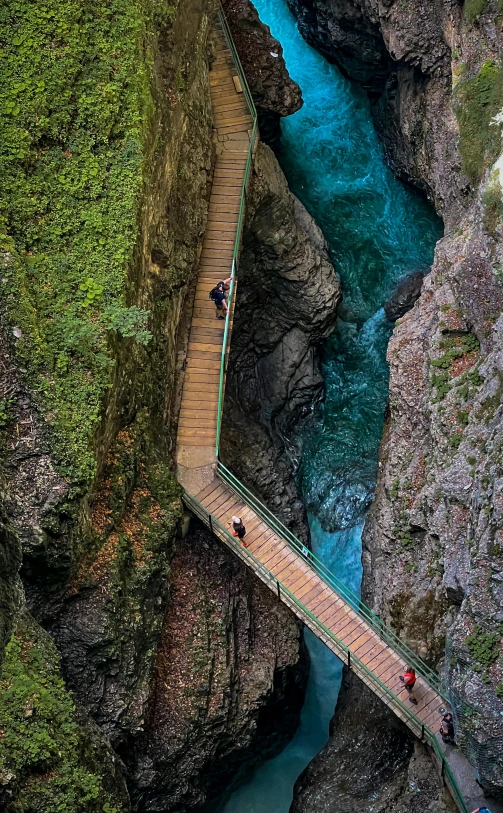 people walking across the walkway over a river