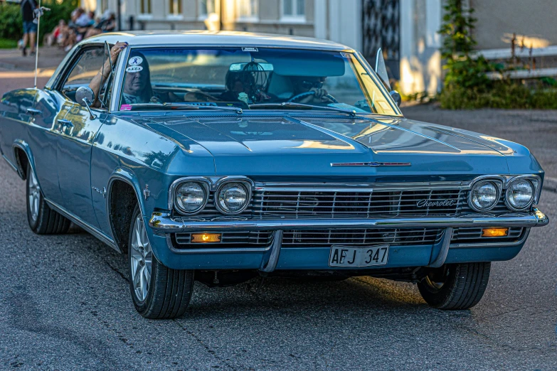 a blue classic car is driving down the road