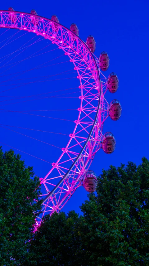 large ferris wheel lit up at night with blue sky