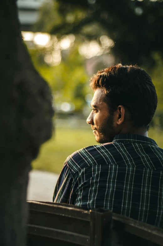 a man sits on a bench in front of a tree