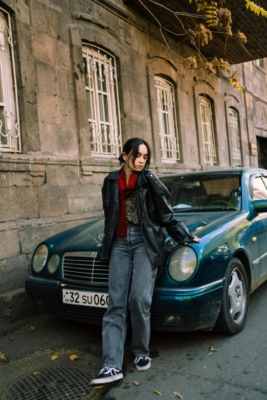 a woman is leaning against a parked car