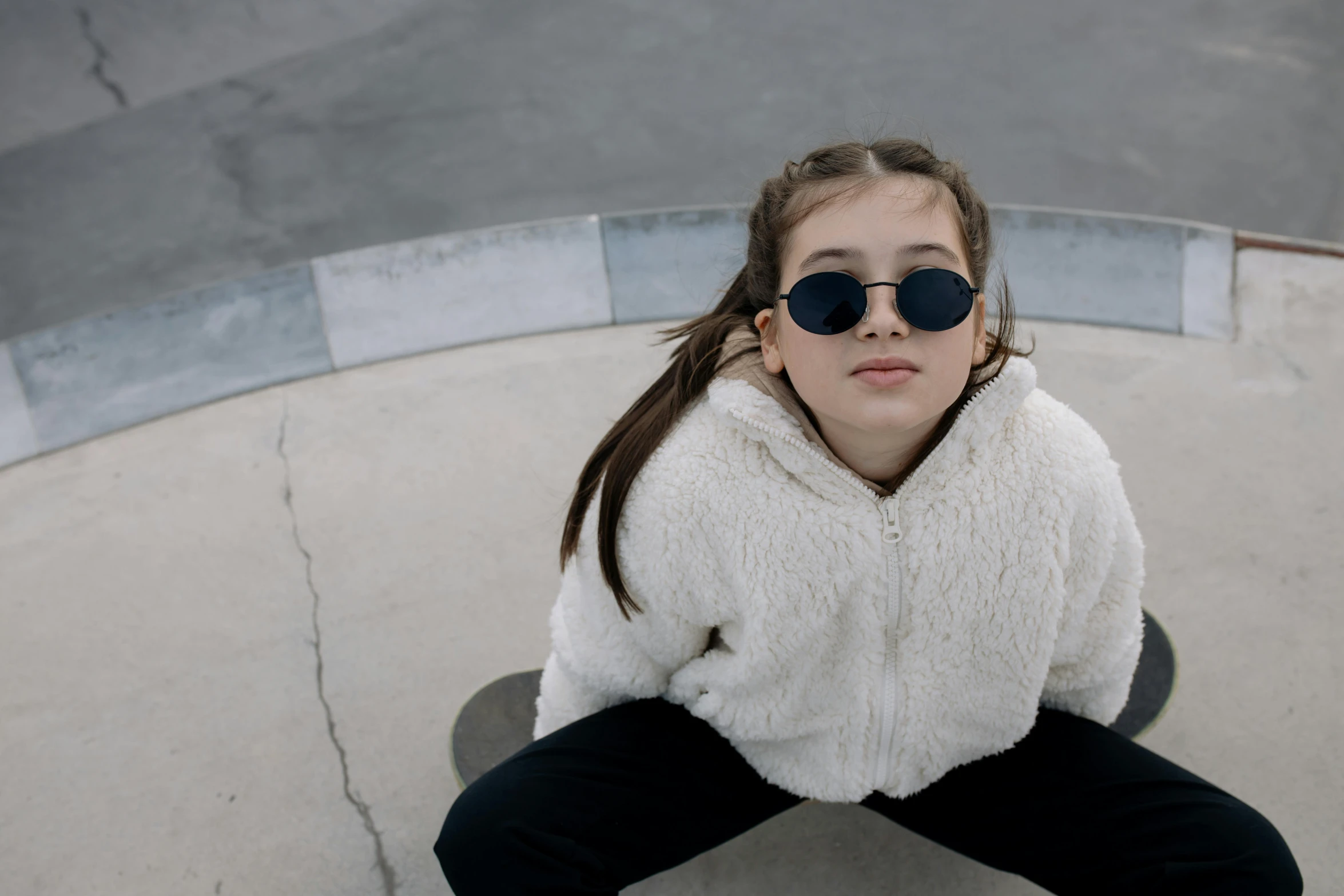 a girl wearing sun glasses sitting on a skateboard