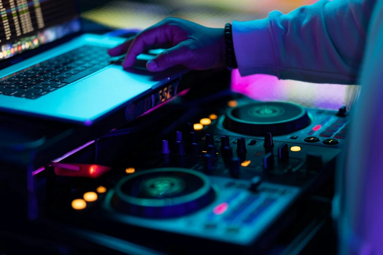 an dj using his laptop, mixing in the music