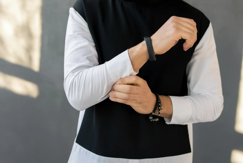 a man adjusting his shirt in a sleeveless outfit