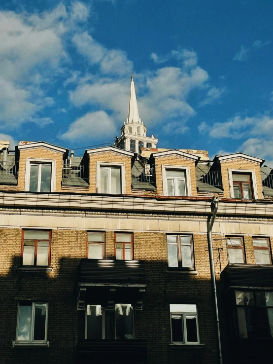 a view of the top part of a building under a blue sky with some clouds