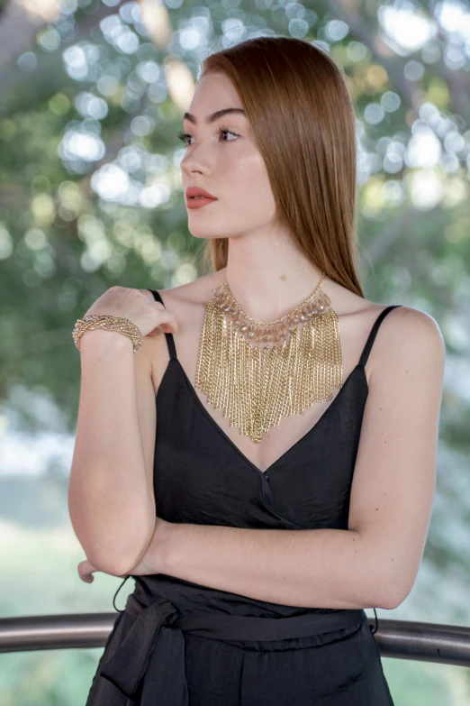 a beautiful young lady wearing a gold statement necklace