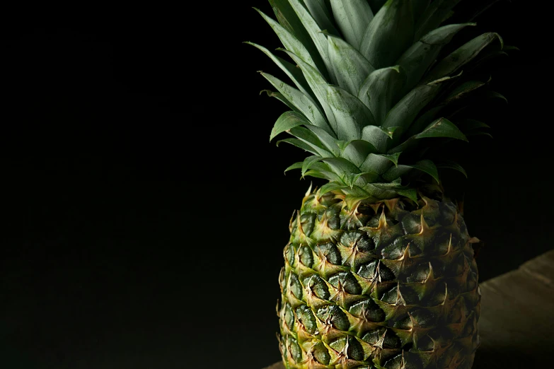 a pineapple with dark background and only the top removed