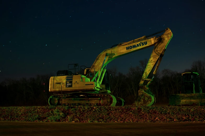 a vehicle with lights on and a backhoe painted green