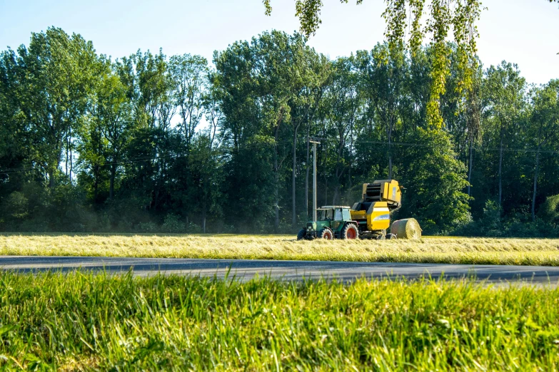 a tractor driving through a field with lots of grass