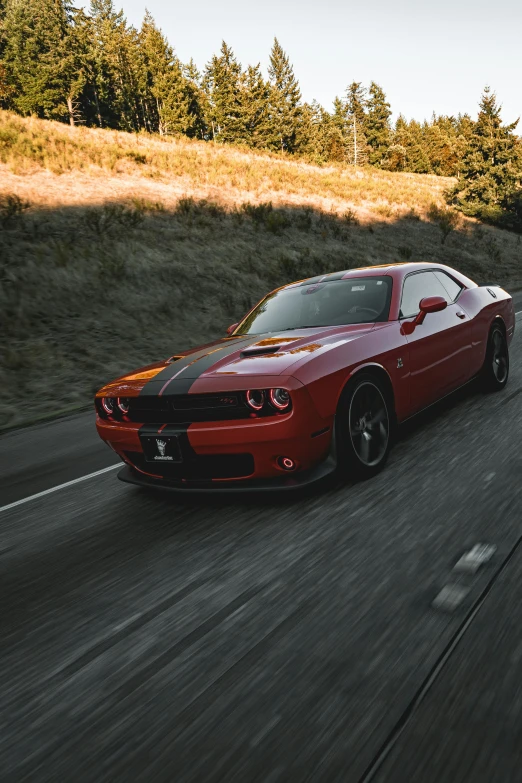 red car driving down a country road on a hillside