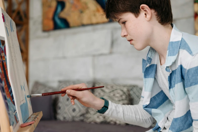 a person sitting down while painting on a easel