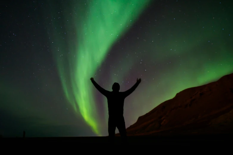 a man standing in front of the auroran sky