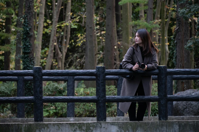 a person leans against a railing while standing in the forest