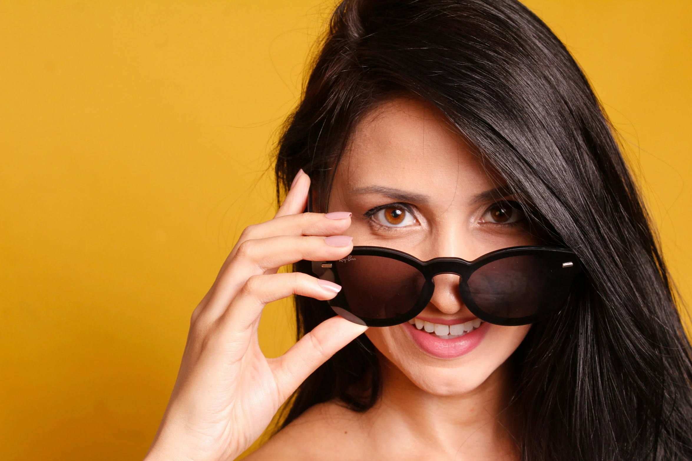 the young woman wears black sunglasses and is smiling