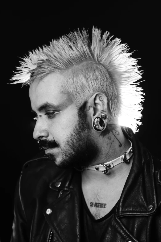 black and white pograph of man with mohawk wearing punk hair