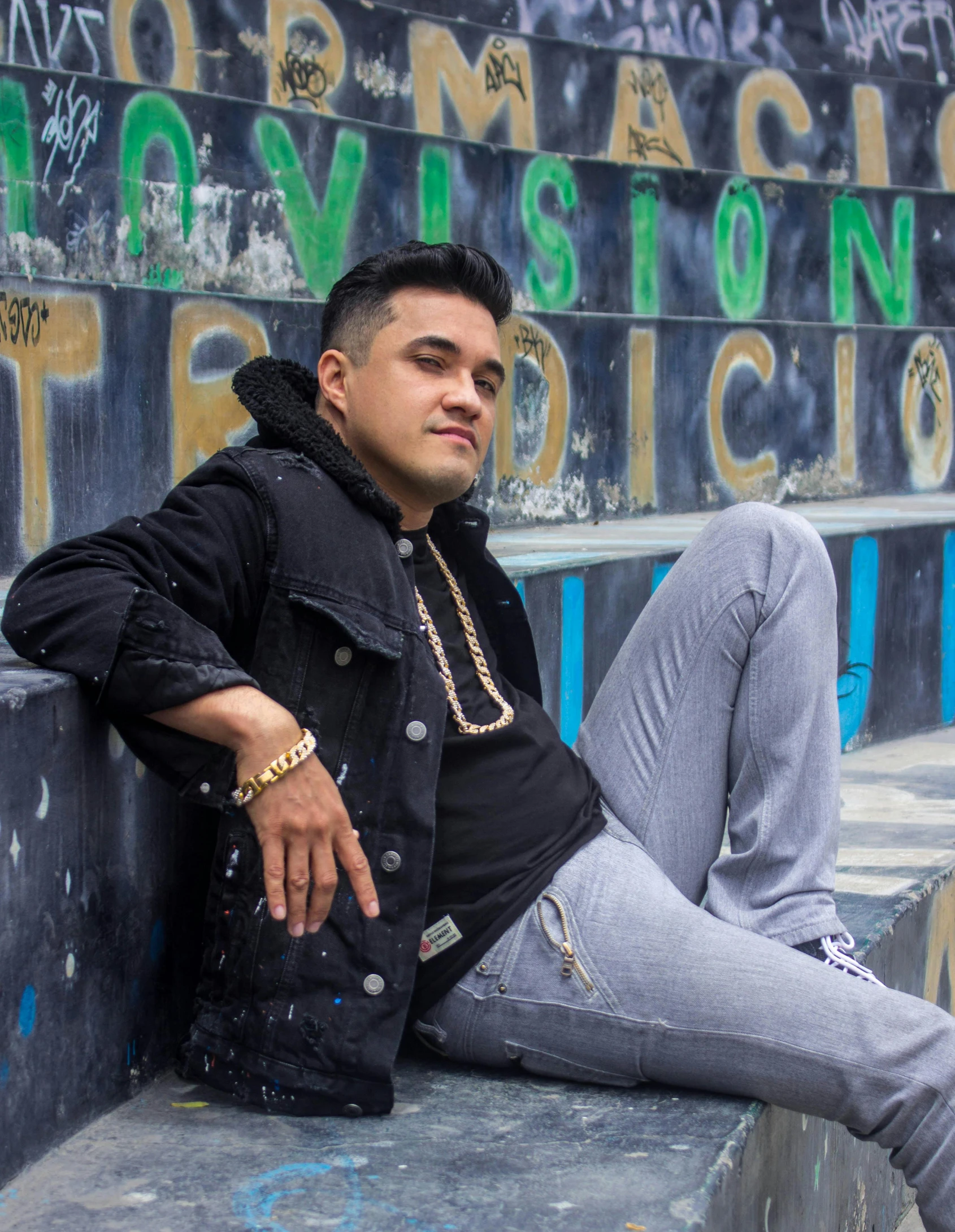 a man with black hair is sitting on a ledge