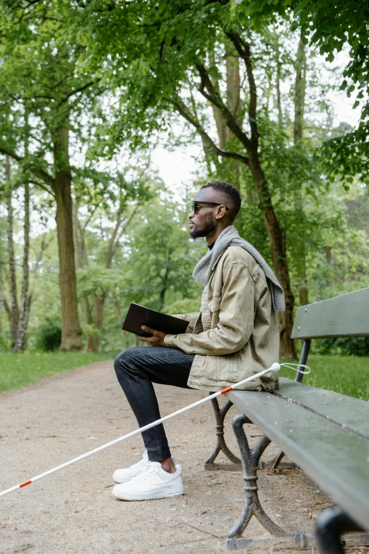 man sitting on bench with notebook in the park