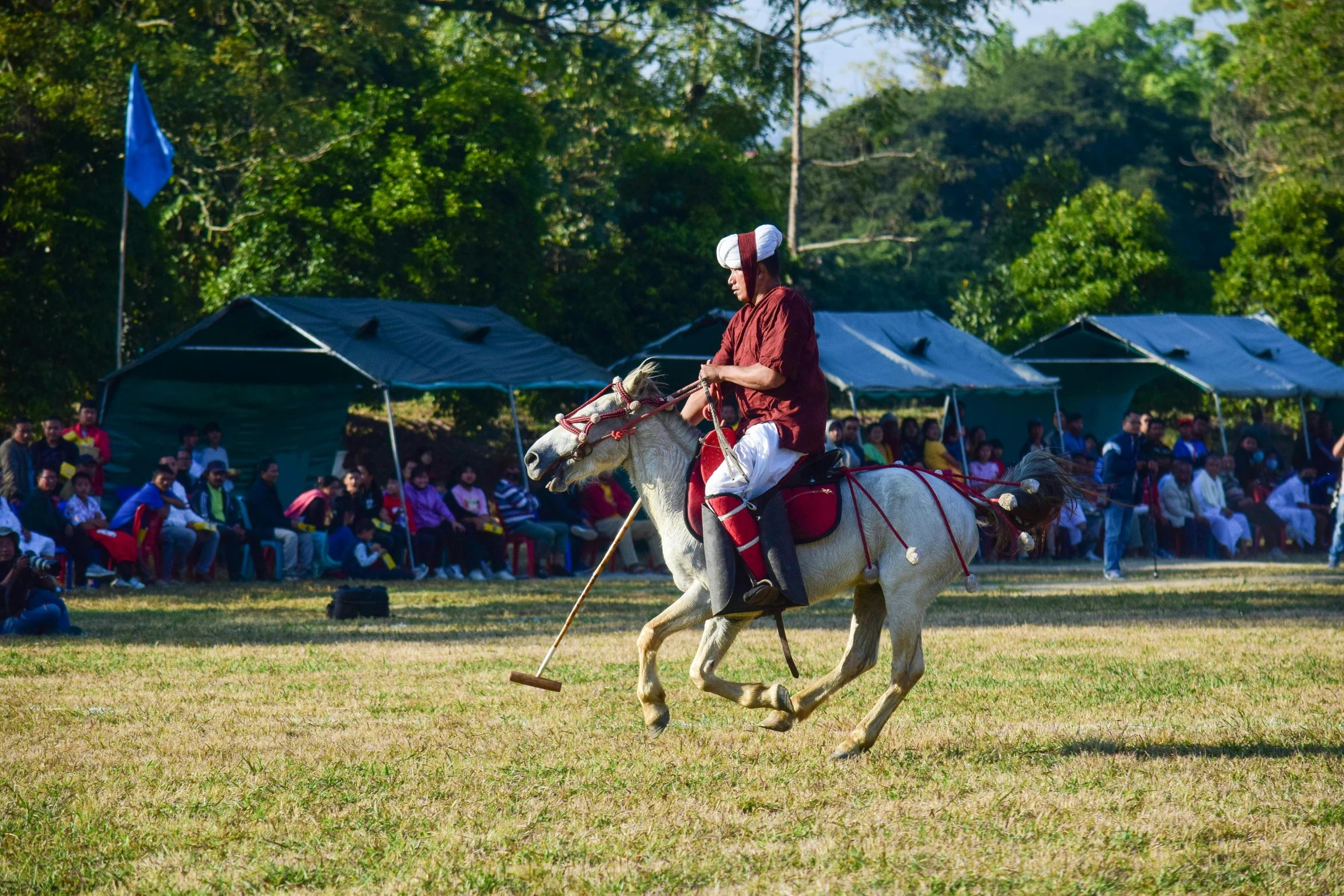 a man riding on the back of a white horse in a field