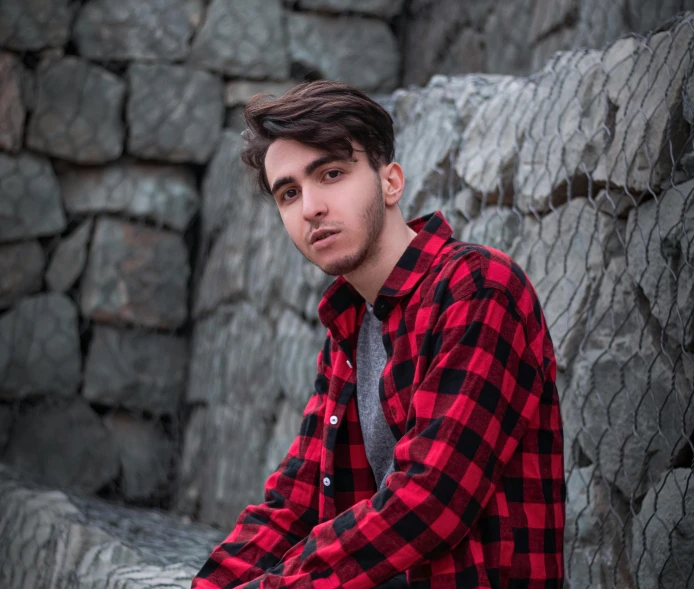 a young man sitting on the edge of a stone wall