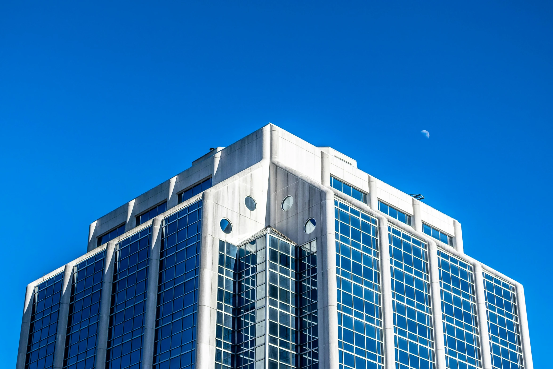 a tall glass and concrete building with blue sky in the background