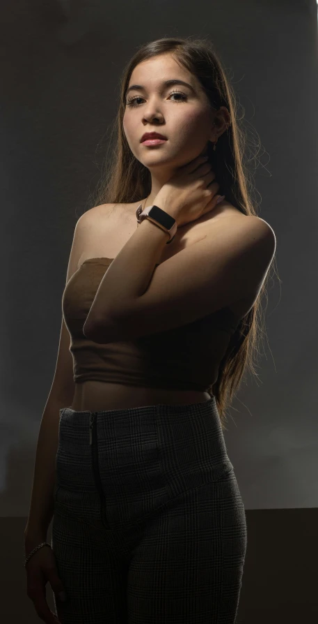 a woman posing in a brown top against a grey background