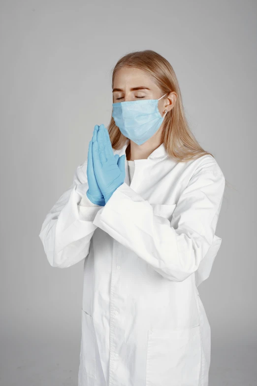 a woman wearing a face mask holding a blue glove
