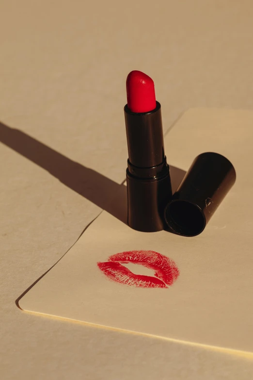 a red lipstick sitting on top of a piece of cardboard