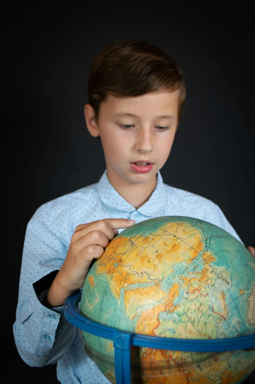 a  examines the globe on a black background