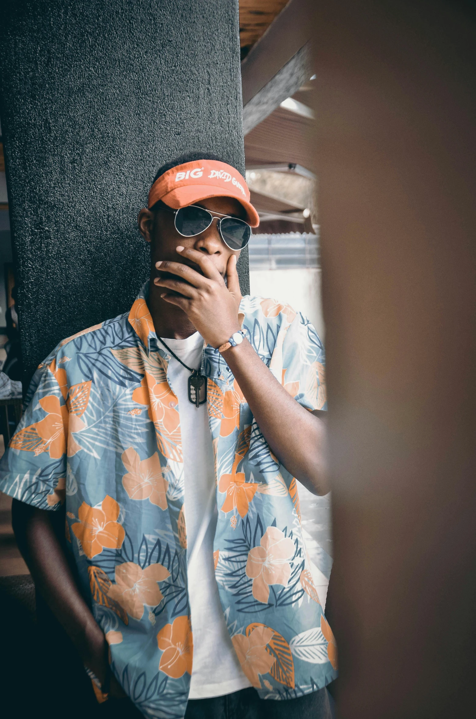 man in orange and blue shirt looking up with large orange hat and sunglasses on