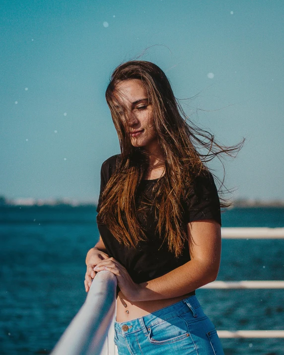 a girl on a ship is holding onto a pole