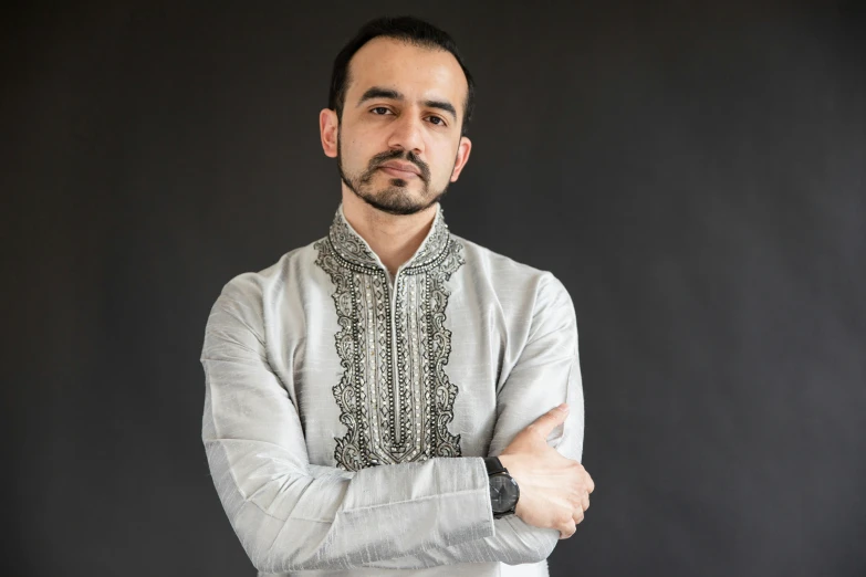 a man with a smile standing with his arms crossed