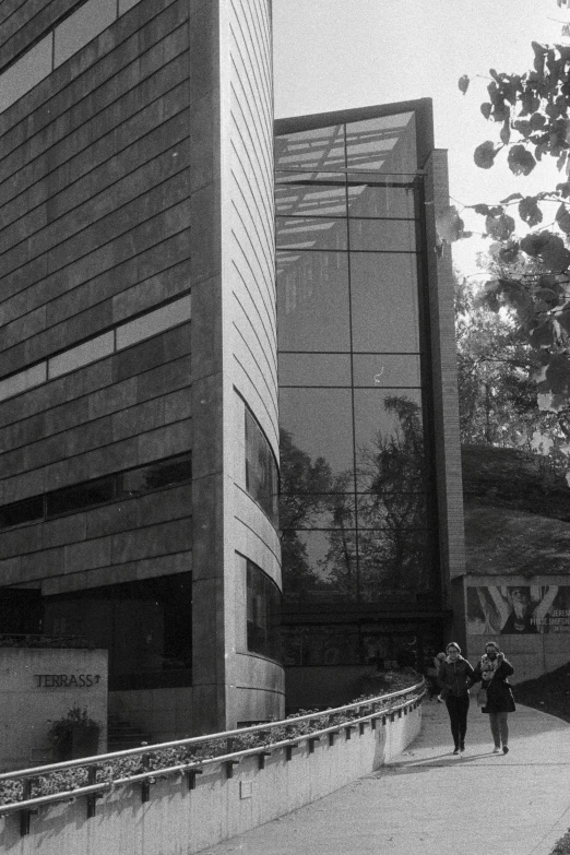 two people walking down a walkway in front of an office building