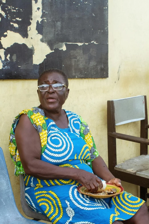 a woman wearing glasses sitting down while eating some food