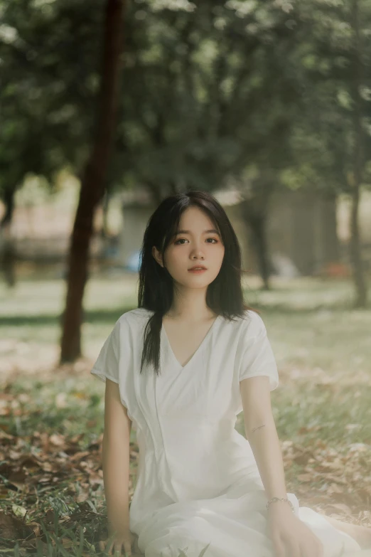 a young asian woman in white sitting on the ground