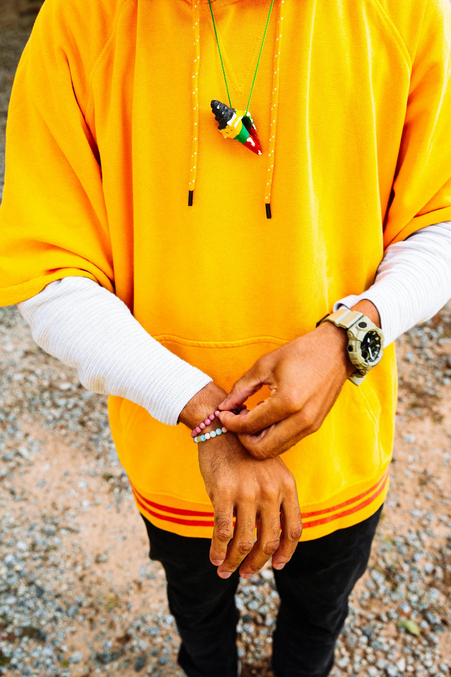 a man standing on a beach wearing a yellow shirt and holding his hand in his pocket