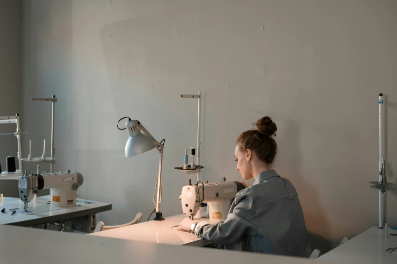 a young woman sitting at a sewing machine working