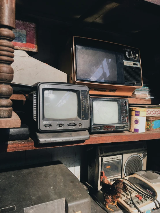 old style televisions sitting on a shelf with many books