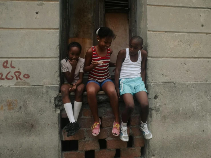 three s sitting on a ledge looking at a phone