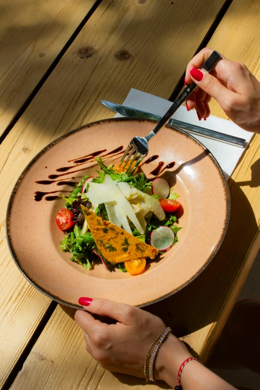 a woman holding a salad on top of a wooden table