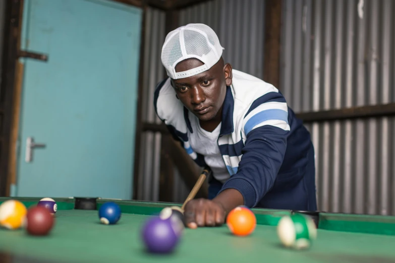 man in a hat playing pool with his pool cues