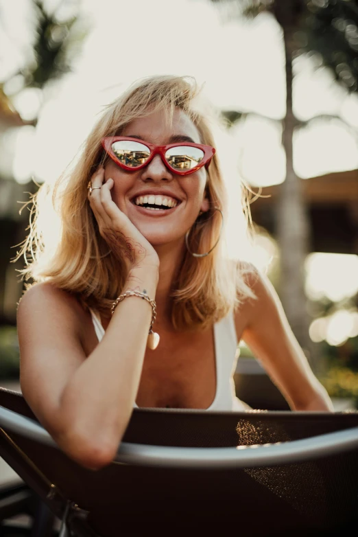 a smiling woman wearing red glasses is talking on her phone