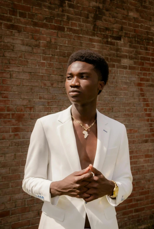 a man in white suit standing against a brick wall