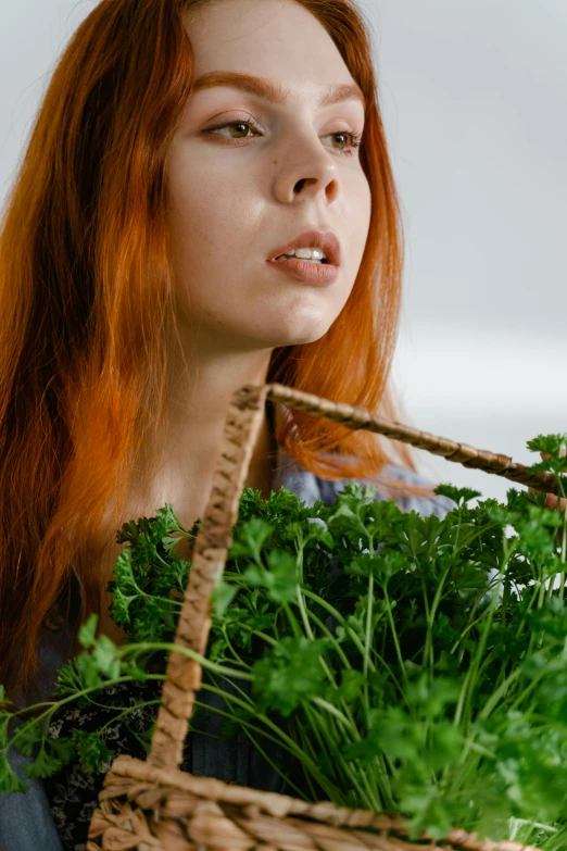 a young woman with red hair holding a basket full of fresh vegetables