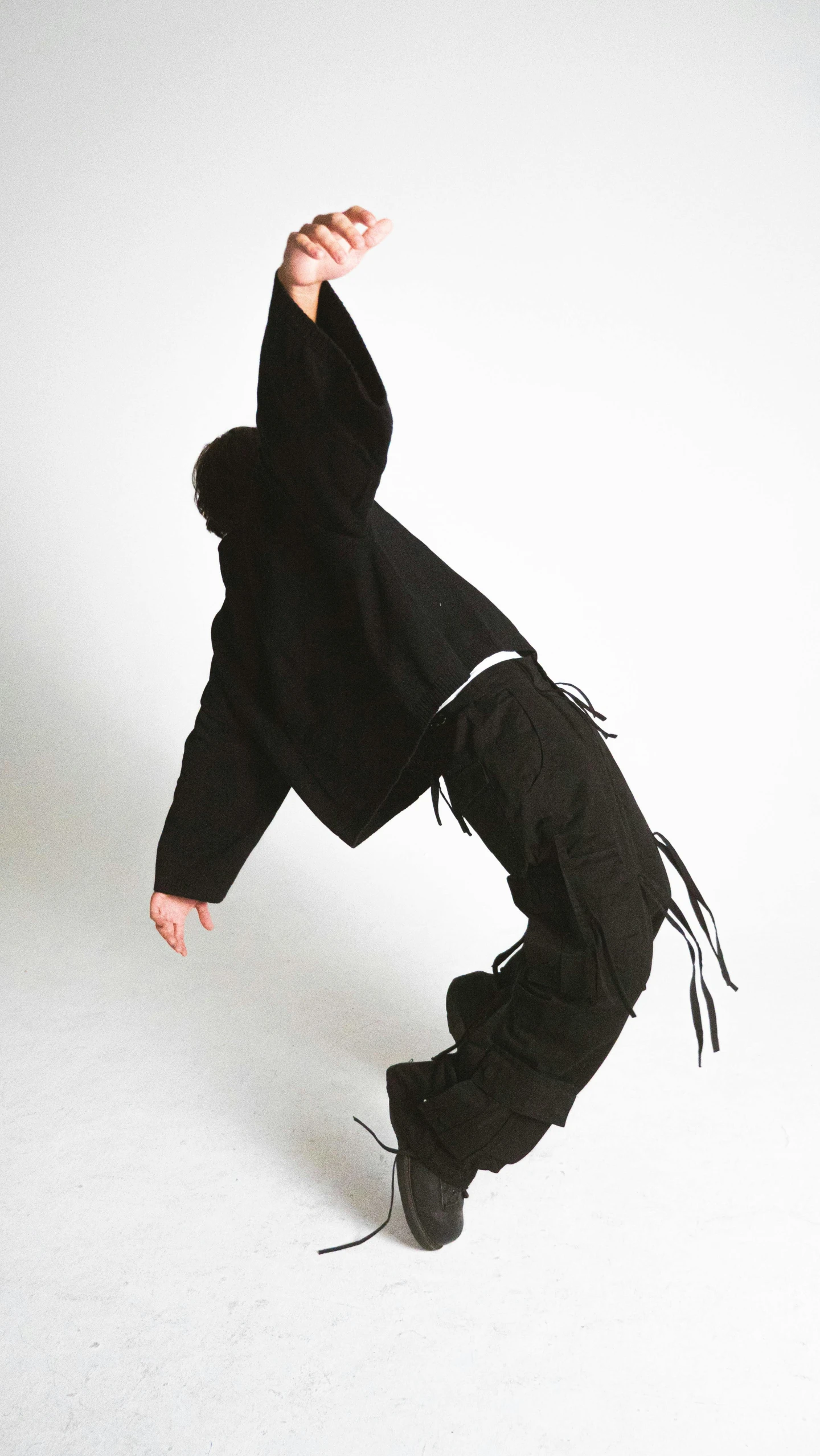 a person wearing black skateboarding against a white backdrop