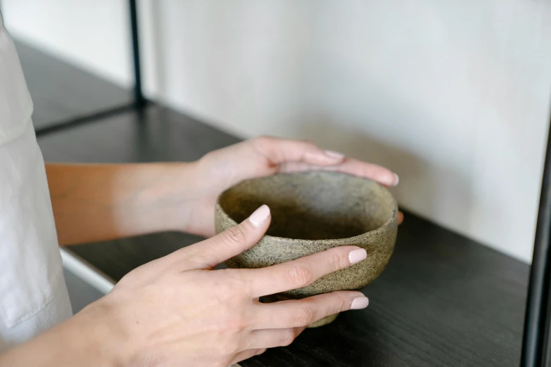 woman holding a clay bowl over a black counter