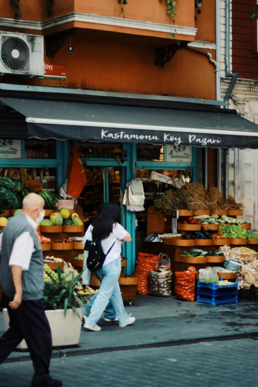 two people walking past an outdoor farmers market