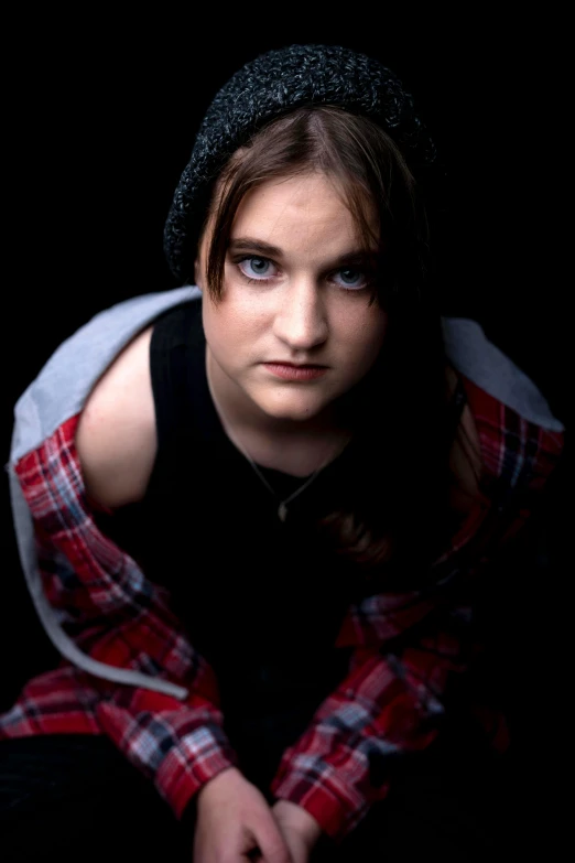 a woman sitting down wearing a hat and sweater