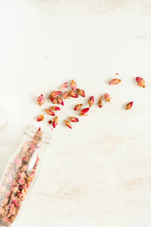 an uncooked jar with various kinds of seeds and flowers spilled out