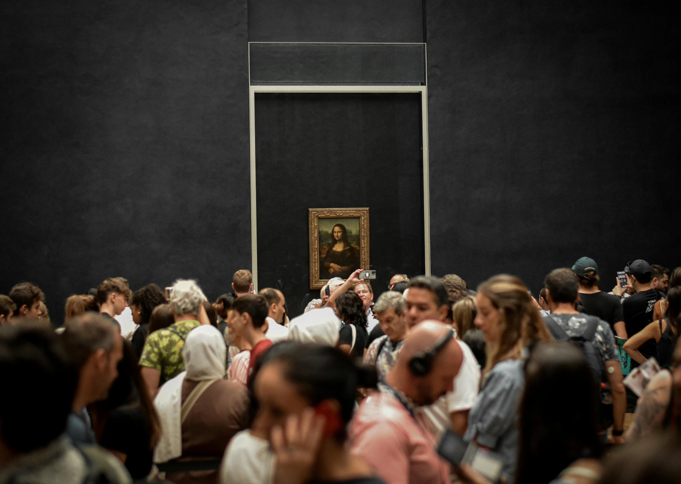 a crowd of people walking around a painting