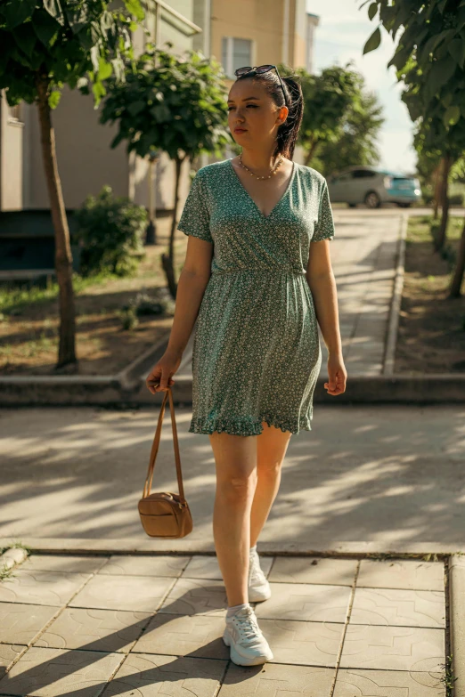 a woman walking down the street holding a tan purse